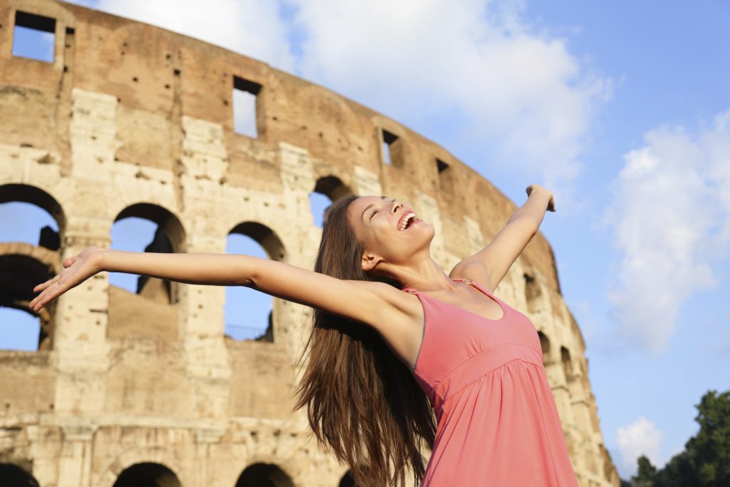 Une voyageuse souriante devant le Colisée à Rome, illustrant les conseils de voyage pour les ressortissants hors Union Européenne