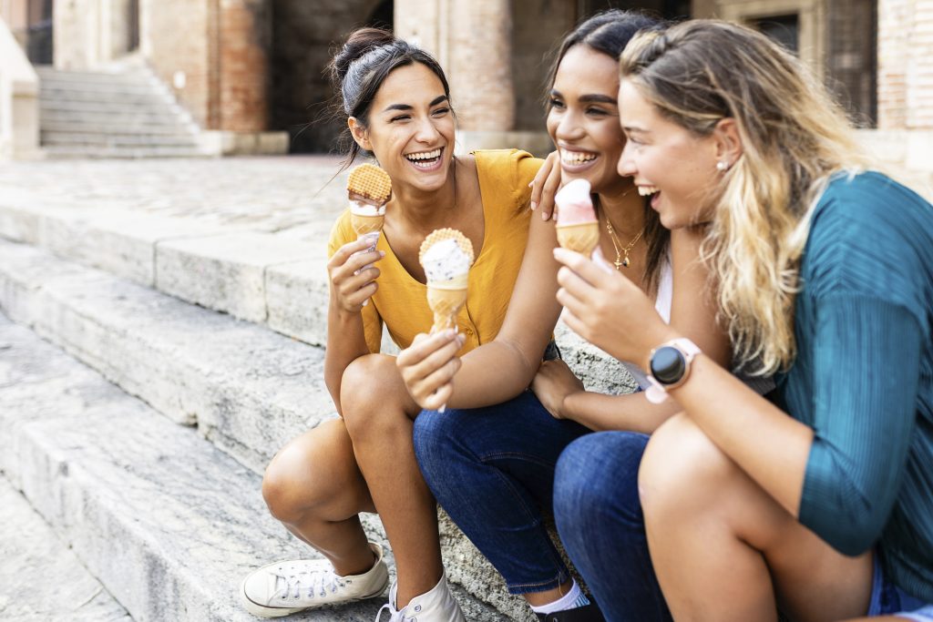 Trois amies savourant des glaces colorées dans une rue charmante de Rome